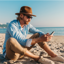 hombre en la playa con celular en la mano